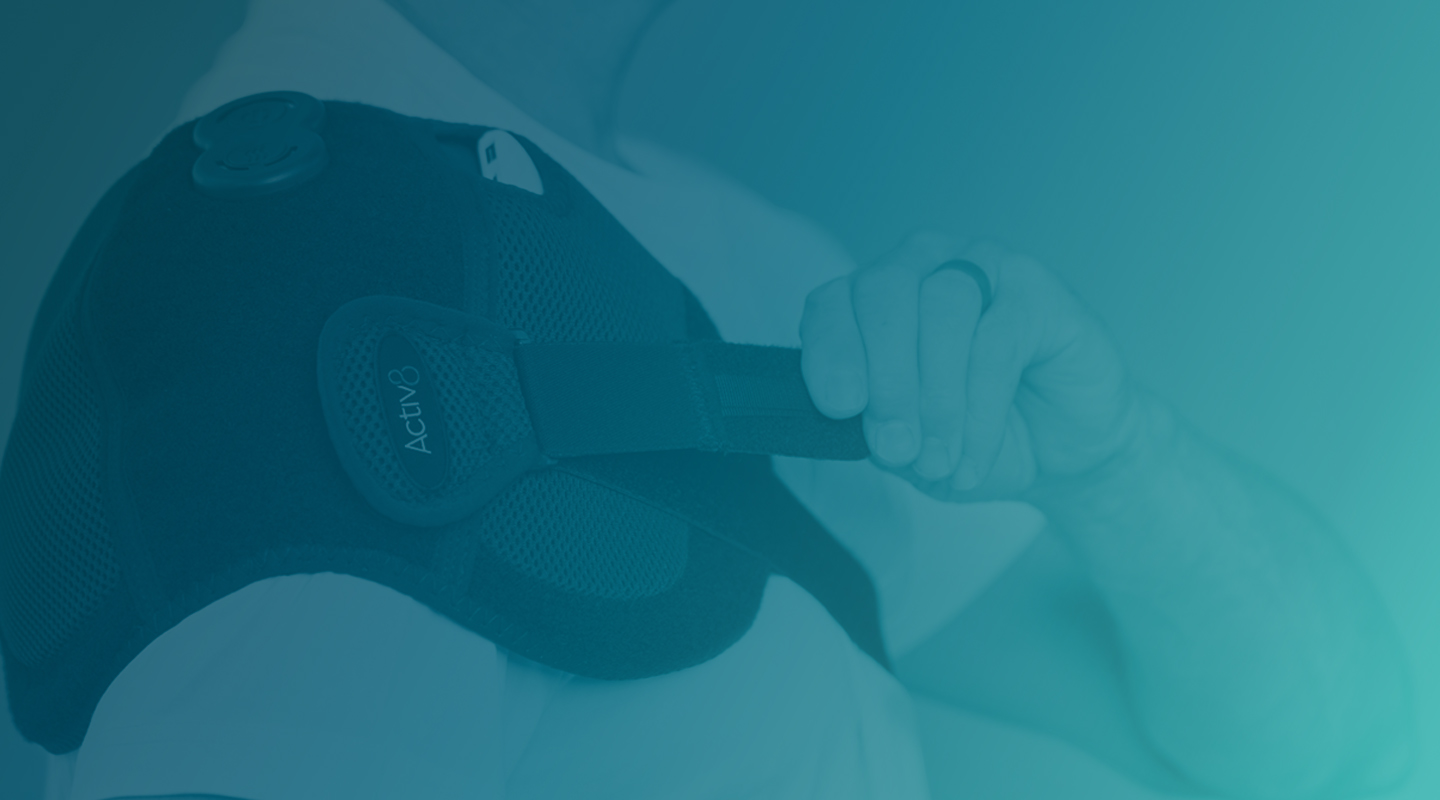 Man wearing the Activ8 Shoulder device, pulling the strap to adjust the fit.